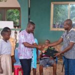 Togbe Dzegblade presents laptop computers to Adaklu Kodzobi Basic School
